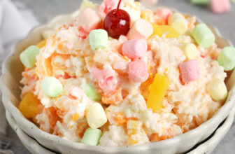 ambrosia salad in a bowl topped with a cherry