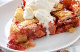 Strawberry Rhubarb Pie on a white plate with vanilla ice cream on top