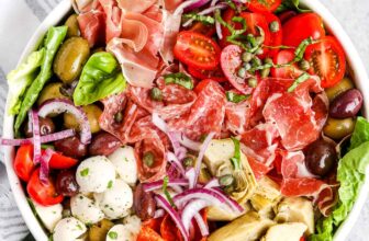 antipasto salad in a while bowl with dressing on the side