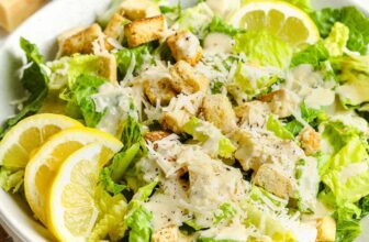 a bowl of caesar salad with lemons