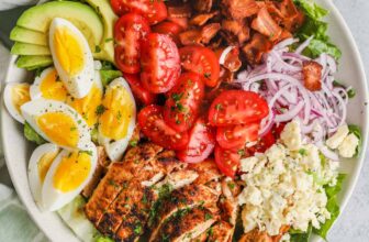 top view of Cobb Salad on a plate with ingredients and dressing around it