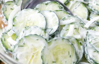 Creamy Cucumber Salad in a mixing bowl being stirred with a spoon