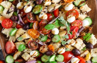 A panzanella salad on a wood board with herbs