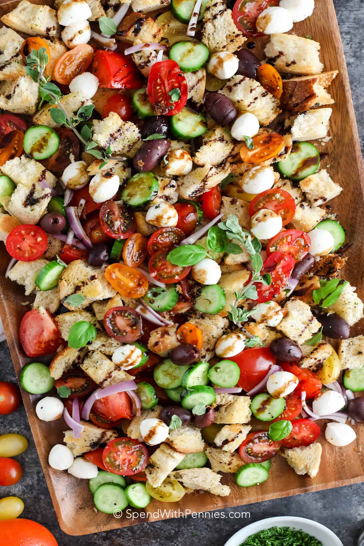 A panzanella salad on a wood board with herbs