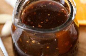 a jar of teriyaki sauce next to orange slices and garlic