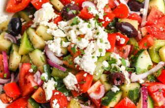 A Greek salad in a while bowl with feta on top
