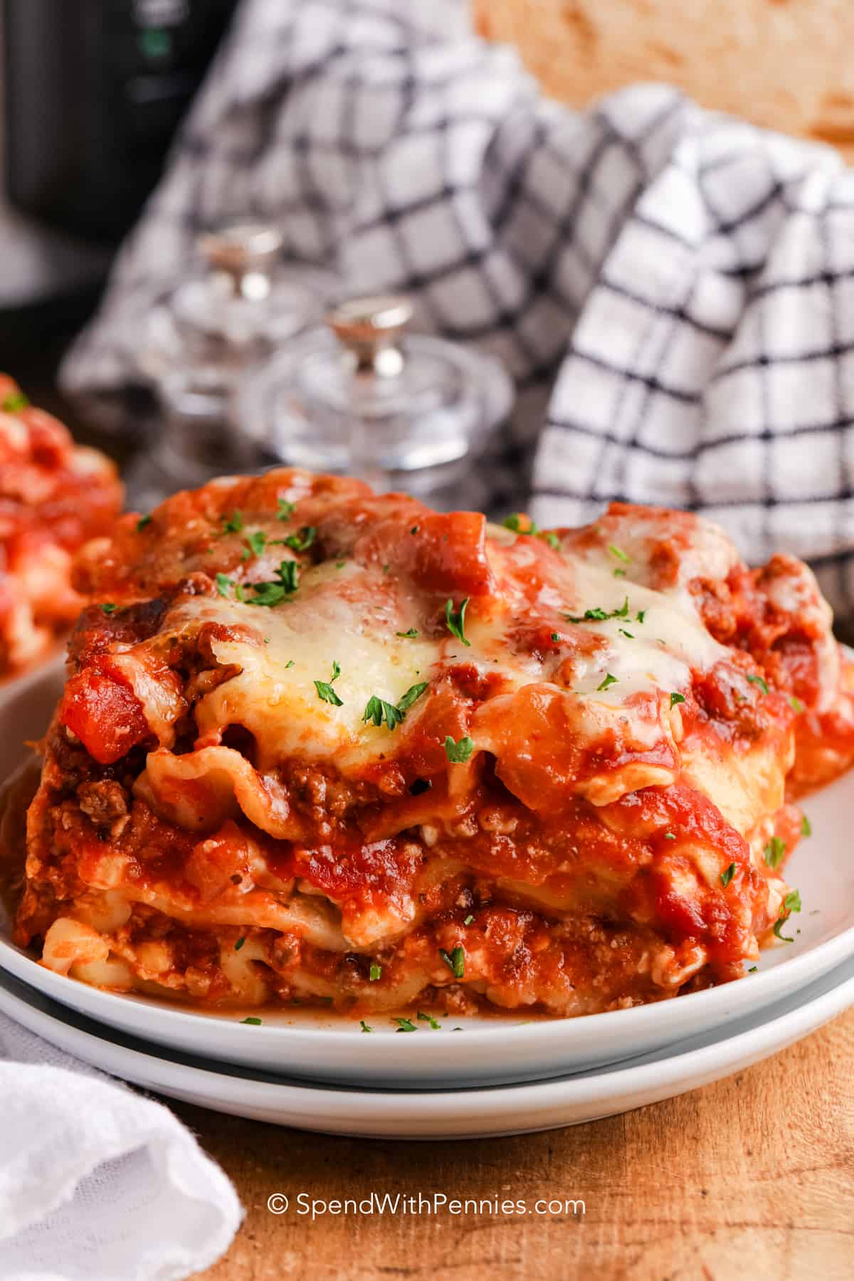 Crock pot lasagna on a plate with garlic bread in a basket.