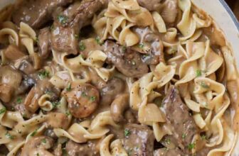 beef stroganoff with egg noodles in a white dutch oven