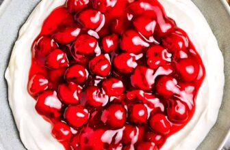 a bowl of cherry cheesecake dip with graham crackers beside it