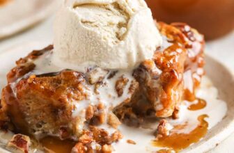 piece of pumpkin bread pudding on a plate with a bite taken out and a scoop of ice cream