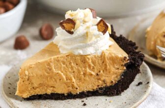 a slice of peanut butter pie on a plate topped with whipped cream