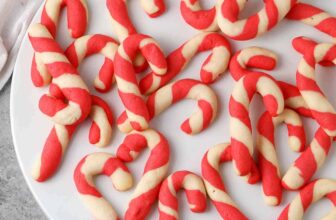 scattered baked candy cane cookies on a white plate