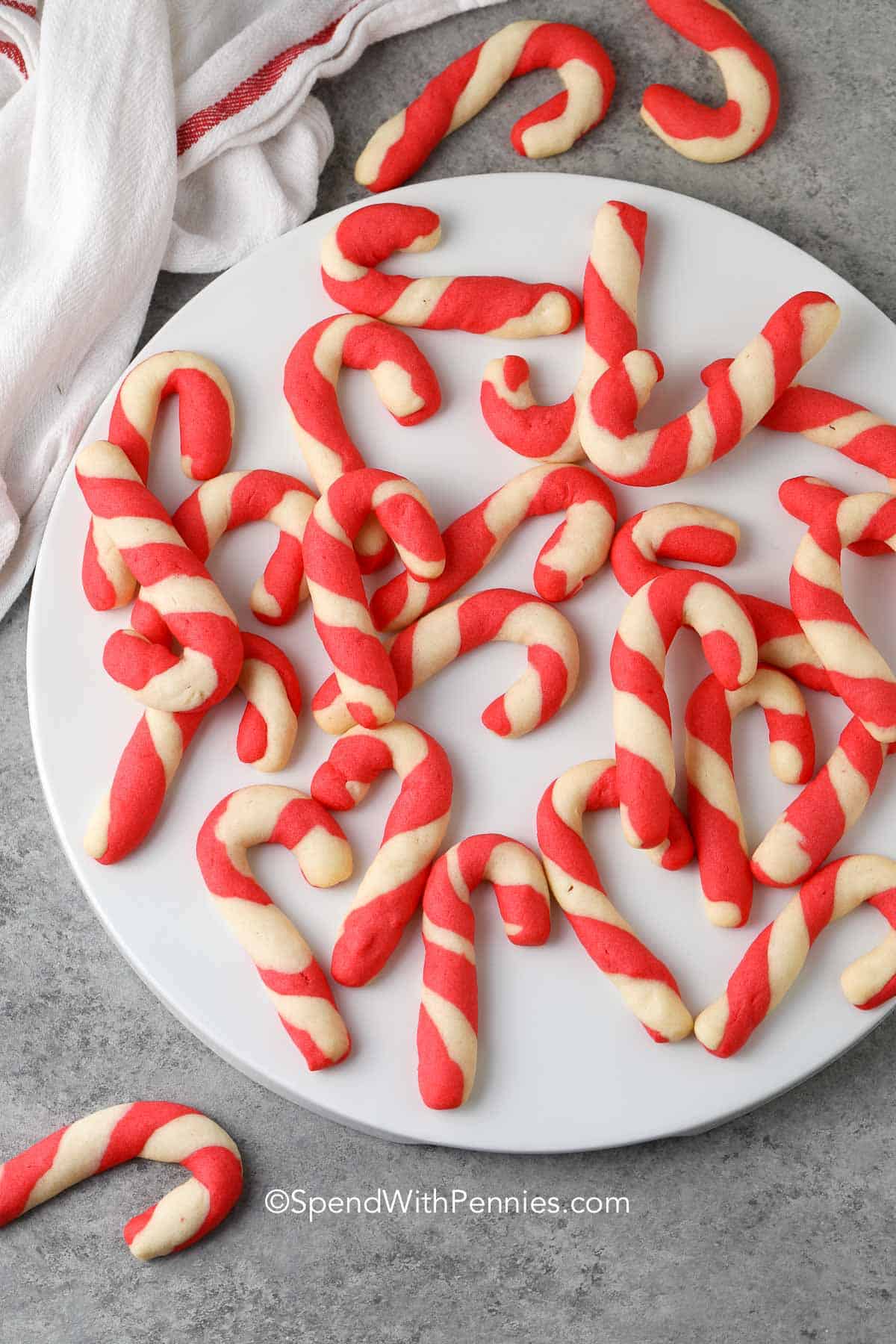 scattered baked candy cane cookies on a white plate