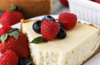 a slice of baked cheesecake on a white plate with berries