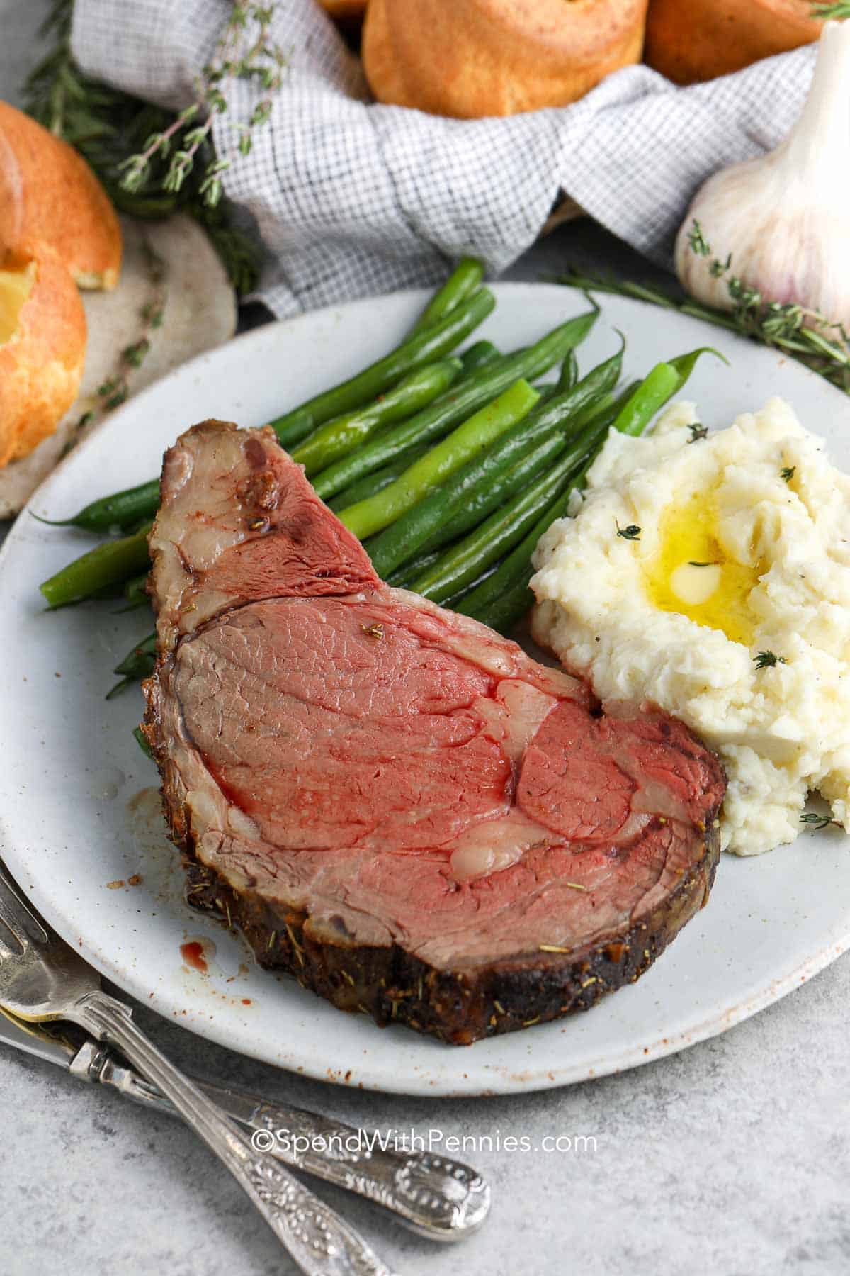 a slice of prime rib with mashed potatoes and green beans on a plate