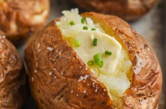 potatoes cooked on a sheet pan with garnish to show How to Make Baked Potatoes