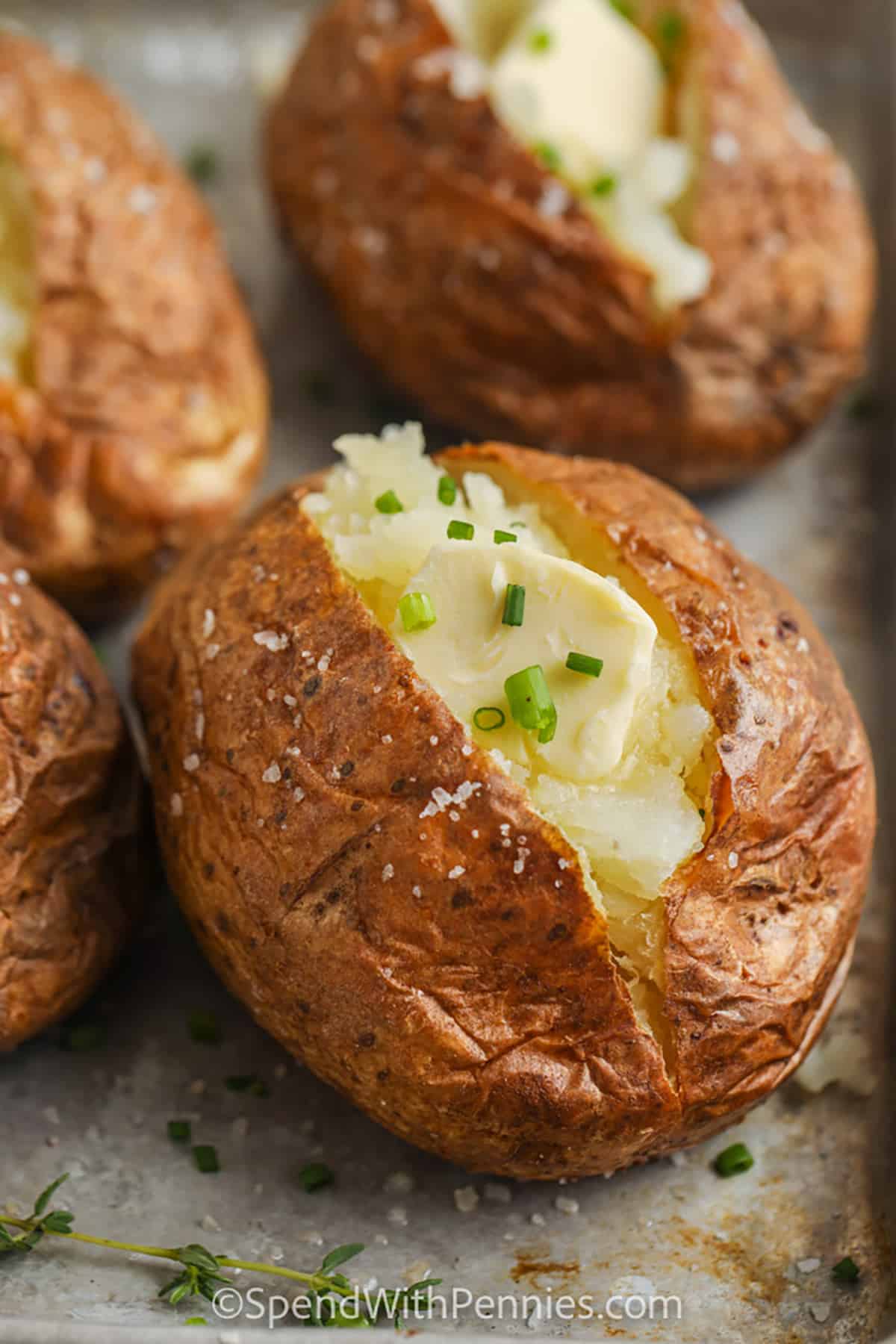 potatoes cooked on a sheet pan with garnish to show How to Make Baked Potatoes