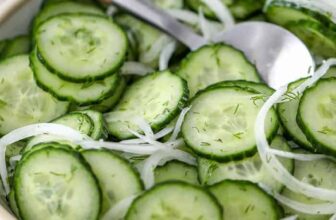 Cucumber Onion Salad in a white bowl with serving spoon