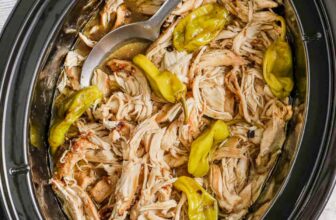 Crock Pot Mississippi Chicken in a slow cooker with a seruing spoon